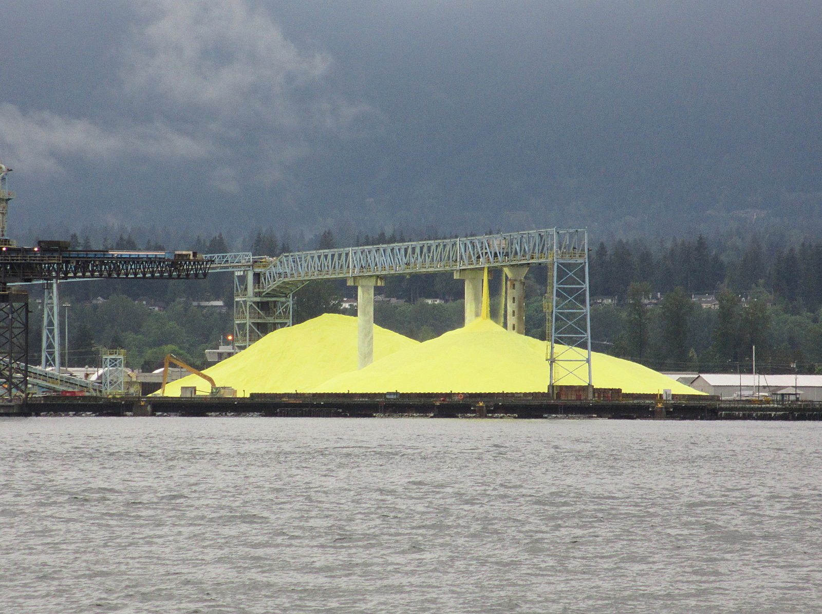 Fig. 5 (Click to enlarge). One of the major reasons for iron sulfide’s very low cost is the low cost of sulfur, which is essentially a waste product. This image shows a sulfur stockpile in Vancouver Harbor.  (Wikimedia Commons)